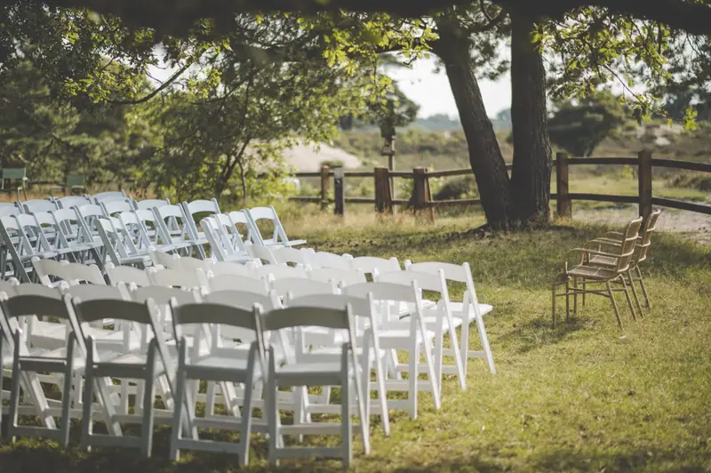 Witte stoelen klaargezet voor een ceremonie onder de bomen
